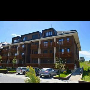 een groot gebouw met auto's geparkeerd op een parkeerplaats bij Zlatibor lux Kalman in Zlatibor