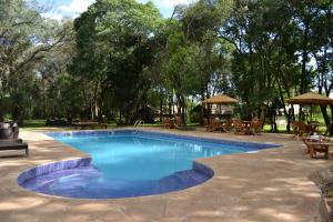 a swimming pool in a yard with tables and umbrellas at Exploreans Mara River Camp in Musiara Campsite +45 photos