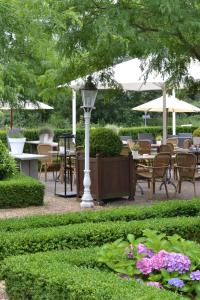 einen Garten mit Tischen, Stühlen und einer Laterne in der Unterkunft Fletcher Hotel Restaurant De Witte Raaf in Noordwijk