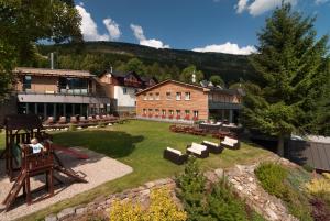 eine Person, die auf einem Stuhl vor einem Gebäude sitzt in der Unterkunft Hotel Olympie in Špindlerův Mlýn