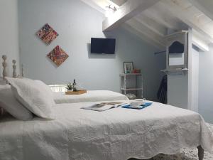 a white bedroom with two beds and a tv on the wall at Casa Anita in Cartagena de Indias