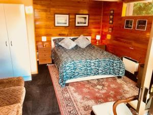 a bedroom with a bed in a room with wooden walls at Cosy studio apartment in Christchurch