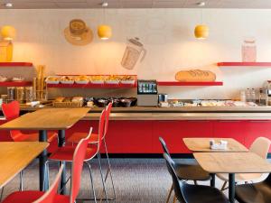 a fast food restaurant with wooden tables and red chairs at ibis Namur Centre in Namur