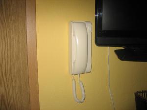 Biały telefon wiszący na ścianie obok telewizora w obiekcie Split Central Guesthouse w Splicie