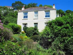 ein weißes Haus mit einem Garten davor in der Unterkunft dog friendly nancecliff cottages in Looe
