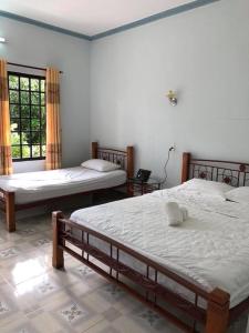 a bedroom with two beds and two windows at Bí Homestay in Mui Ne