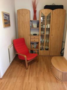 einen roten Stuhl in einem Zimmer mit Bücherregal in der Unterkunft Ferienwohnung "Die 14" in Steinach am Brenner