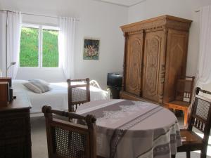 Laroque-des-AlbèresにあるLe Quatorzeのベッドルーム1室(ベッド1台付)、大きな木製キャビネットが備わります。