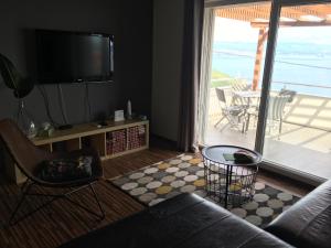 ein Wohnzimmer mit einem Sofa, einem TV und einem Balkon in der Unterkunft Apartment Selce Kala in Mošćenička Draga