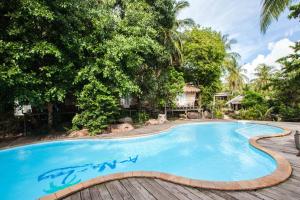 una piscina con una terraza de madera y árboles en A-Na-Lay Resort Koh Kood en Ko Kood