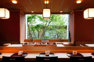 a dining room with a large window and tables and chairs at Hotel Okura Kobe in Kobe