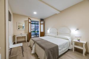 - une chambre avec un lit blanc et une chaise dans l'établissement Pensión Luis, à Arzúa