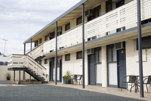 un edificio con mesas y sillas fuera de él en Pioneer Station Motor Inn, en Swan Hill