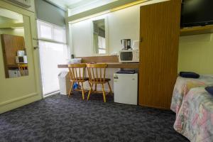 a room with two beds and a desk with a microwave at Pioneer Station Motor Inn in Swan Hill