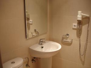 a bathroom with a sink and a toilet and a mirror at S'Arenal Apartments in Portinatx