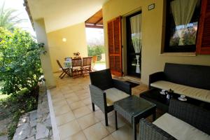 un patio con sillas, un sofá y una mesa en Trilocale Turagri 45 en Costa Rei