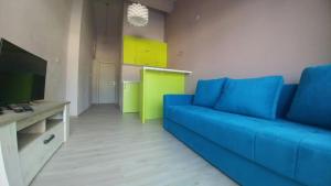 a living room with a blue couch and a kitchen at Apartman Bećir in Budva