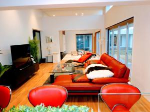 sala de estar con sofá naranja y sillas rojas en Amore Miyakojima, en Isla Miyako