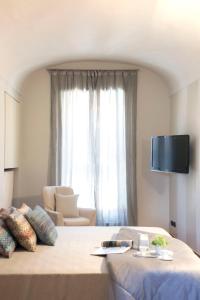 um quarto com uma cama, uma televisão e um sofá em La Finestra sul Borgo em Alba