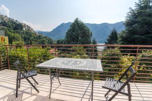 a table and two chairs on a balcony with mountains at Villa Vittoria - The House Of Travelers in Cernobbio