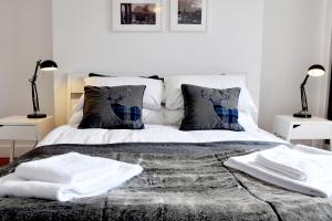 um quarto com uma cama com lençóis brancos e almofadas em Stylish Flat in 1860's Listed Building em Edimburgo