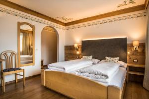 1 dormitorio con 1 cama grande y espejo en Ciasa Montanara en La Villa