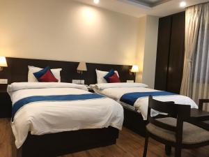 a hotel room with two beds and a desk at Kaveri Inn in Kathmandu