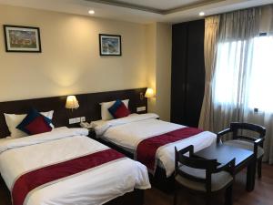 a hotel room with two beds and a table at Kaveri Inn in Kathmandu