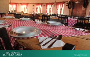 a table with plates and silverware on a red and white table cloth at House Korina B&B in Ličko Petrovo Selo