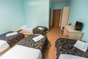 a room with three beds and a desk with a computer at Hotel Solovetskaya Sloboda in Solovetsky Islands