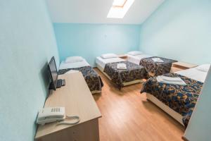 a room with four beds and a desk with a computer at Hotel Solovetskaya Sloboda in Solovetsky Islands