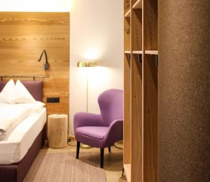 a bedroom with a bed and a purple chair at Chalet Silvretta Hotel & Spa in Samnaun