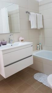 a white bathroom with a sink and a bath tub at The Shining Star -A beautiful 3 bedroom apartment in Beer Sheva