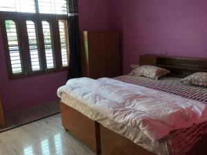 a bed in a room with purple walls and windows at CHÉRI HOME Stay in Khajurāho