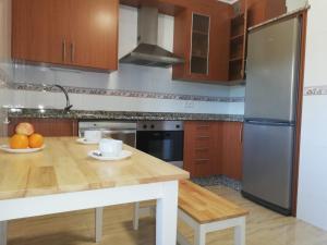 a kitchen with a wooden table and a refrigerator at Pedrouzo Suites in O Pedrouzo