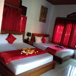 two beds in a room with red curtains at Kuwera Homestay in Nusa Penida