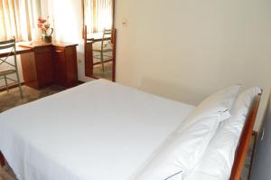 een slaapkamer met een wit bed in een kamer bij Hotel Lago das Pedras in Apucarana