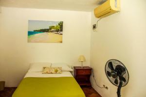a room with a bed and a fan and the beach at Sunshine Lodge: Your home away from home in Montego Bay