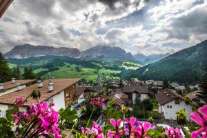 a town in the mountains with flowers in the foreground at Ciasa Montanara in La Villa
