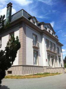 um grande edifício branco com janelas e um telhado em La Demeure des 2 Trésors em La Bresse