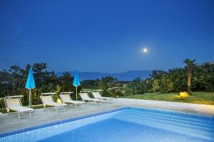 a swimming pool with lounge chairs and umbrellas next to at Apartments Juranic I in Baška