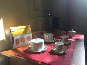 einen Tisch mit drei Kaffeetassen und einer Schachtel darauf. in der Unterkunft La Plaisance du Palais garage sur place sous condition in Avignon