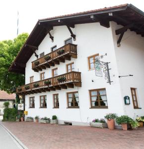 a white building with wooden balconies and potted plants at Hotel Haflhof in Egmating