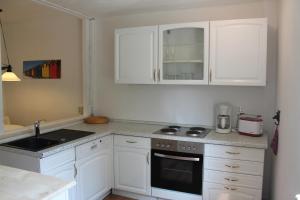 a kitchen with white cabinets and a stove top oven at Ferienappartements am See in Schorfheide