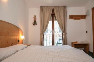 sypialnia z łóżkiem i dużym oknem w obiekcie Albergo Mezzolago w mieście Mezzolago