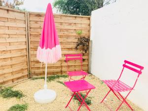 two pink chairs and a pink umbrella in a yard at CosyStudio2 Site du Futuroscope in Jaunay-Marigny