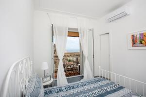 ein weißes Schlafzimmer mit einem Bett und einem Fenster in der Unterkunft Maison Ortigia in Syrakus