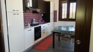 a kitchen with a table and a white refrigerator at Villa Cloe in San Vito lo Capo