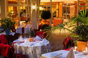 un restaurante con mesas con manteles y plantas blancas en Romantik Hotel Rindenmühle en Villingen-Schwenningen