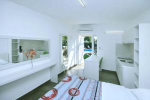 a white room with a bed and a desk and a sink at Apartmani Elio in Umag
